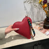 A red heart-shaped PU coin purse with a black and yellow strap is displayed on a light countertop.