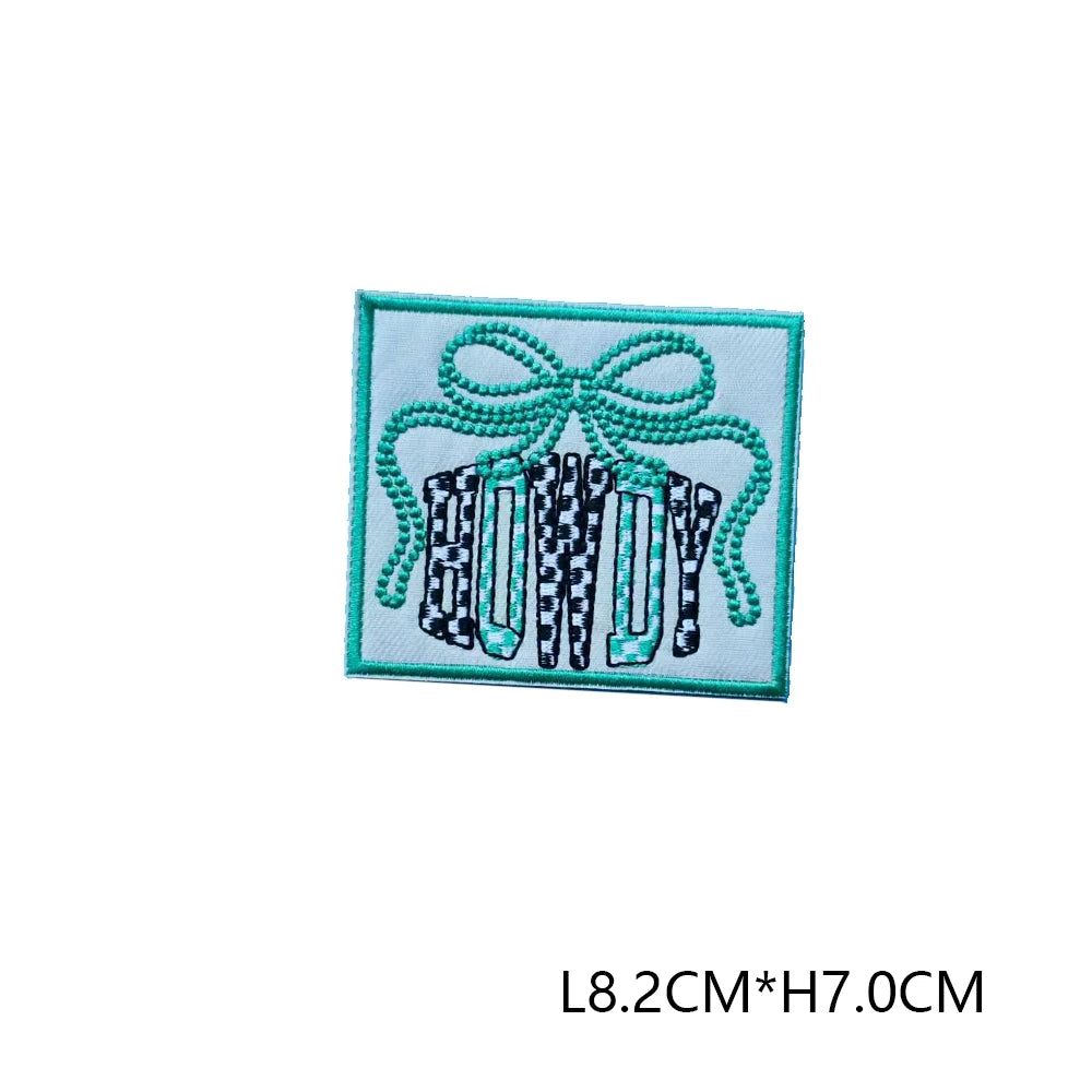 Green embroidered letter patch featuring a bow and three vertical rectangular letters.