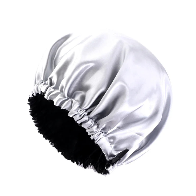 A white satin sleep bonnet with ruffled edges and a black faux fur trim.
