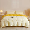 A light yellow quilted duvet cover set with matching pillowcases displayed on a bed.