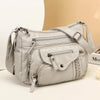 A light gray classic leather tote bag with a padded design and adjustable strap is shown against a neutral background.