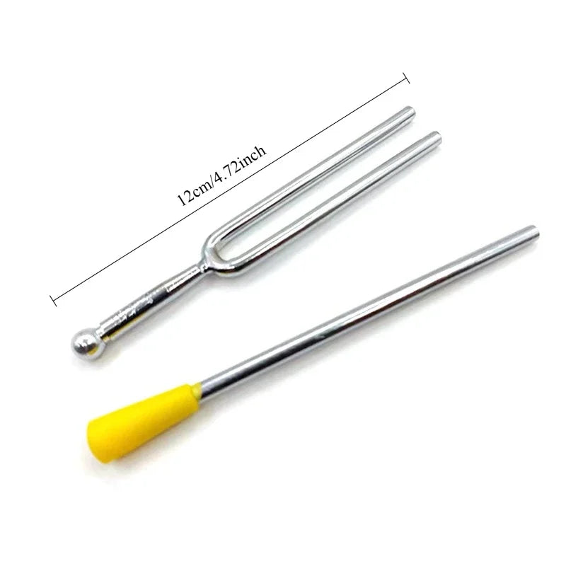 A silver tuning fork set with a yellow activator, shown against a white background.