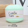 A ball of light green cotton yarn labeled as Cotton Yarn 100g, shown on a wooden surface.