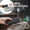 A hand holds a black slim pop-up wallet with RFID blocking technology and an electronic device.