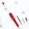 A set of ten red beaded ballpoint pens lying on a white tiled surface.