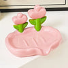 A pink tulip drainage soap dish with green plant-shaped soap holders on a white surface.