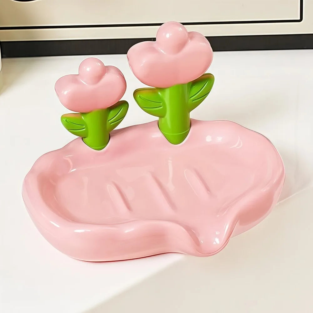 A pink tulip drainage soap dish with green plant-shaped soap holders on a white surface.