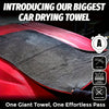 A close-up of a large gray microfiber drying towel being used to clean the surface of a red car.