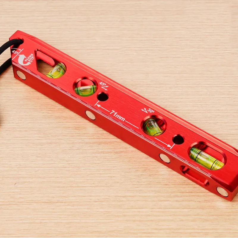A red magnetic aluminum level ruler with V-grooves for precise angle measurement is shown on a wooden surface.