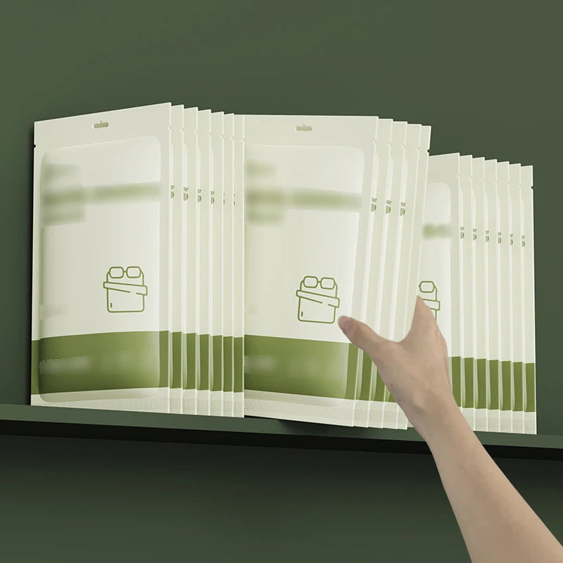 Une main tient une pile de draps jetables pour lit double, montrant l'emballage transparent.