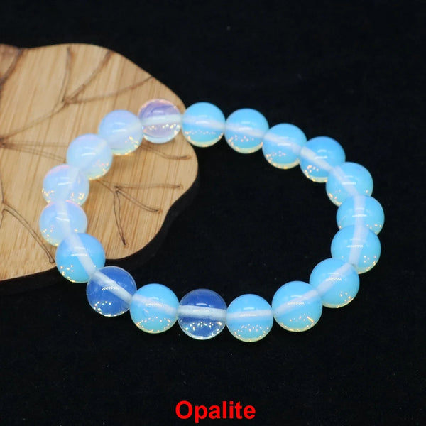 A bracelet made of opal beads is displayed next to a piece of light wood.