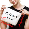 A white toiletry bag with black text reading CRAP BAG shown being held by a person.