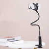 A black flexible gooseneck phone holder with a white smartphone attached, resting on a white table.