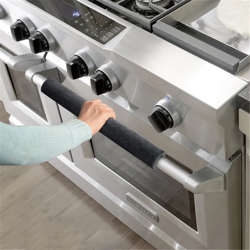 A hand is adjusting a soft velvet anti-skid handle cover on a stainless steel kitchen appliance.