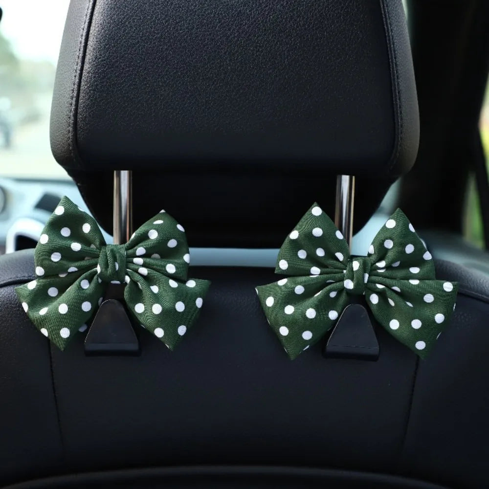 A black car seat back hook featuring a bow-shaped green and white polka dot fabric for storage.