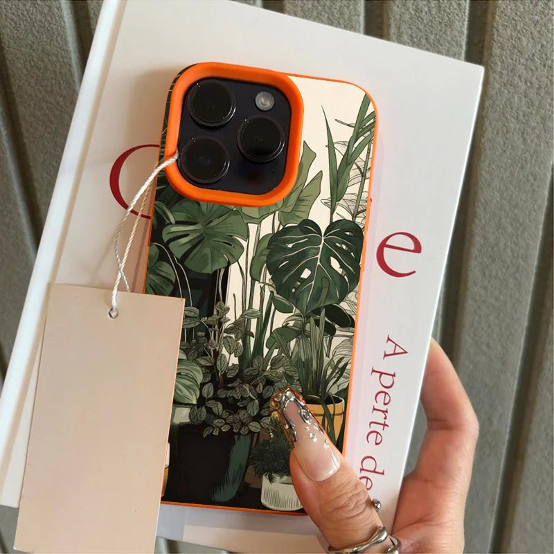 A close-up of a phone case featuring a green monstera plant pattern with orange accents.