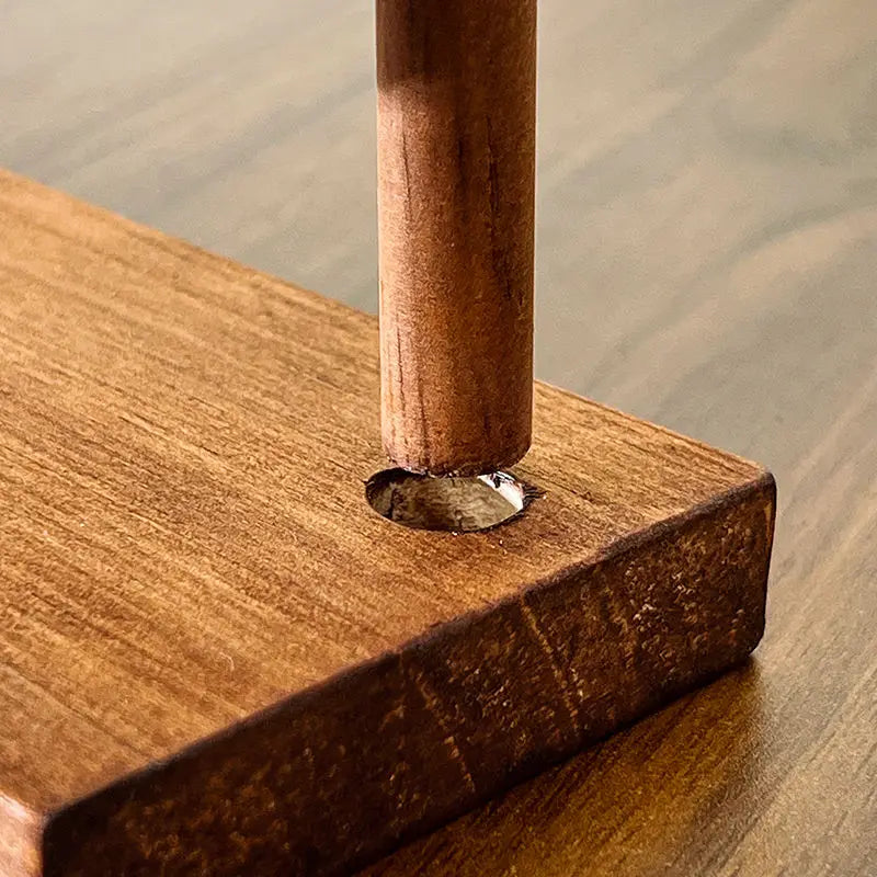 Gros plan d'un organisateur de bijoux en bois avec un crochet suspendu vertical inséré dans une base en bois.