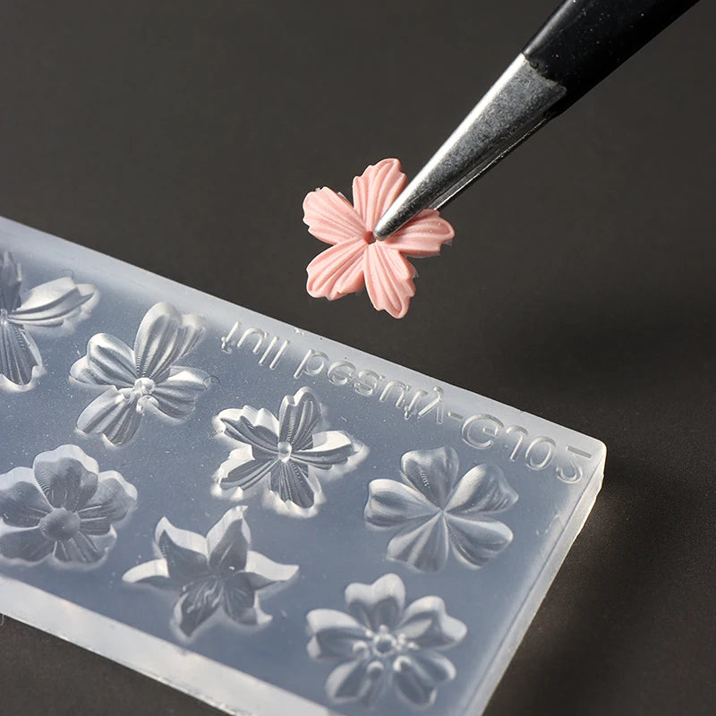A silicone nail art mold featuring a pink floral design is being pressed by a fine tool.