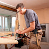 A man is using a durable hammer holder for tool belts while working on a wooden table.