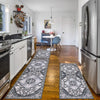 A long, patterned gray and white kitchen rug lies on a wooden floor in a bright room.