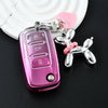 A pink soft TPU car key cover with a keyring and a silver butterfly charm resting on a black surface.