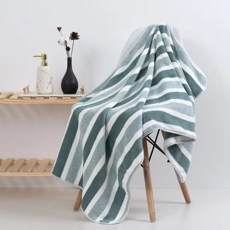 A gray and white striped microfiber bath towel draped over a wooden stand.