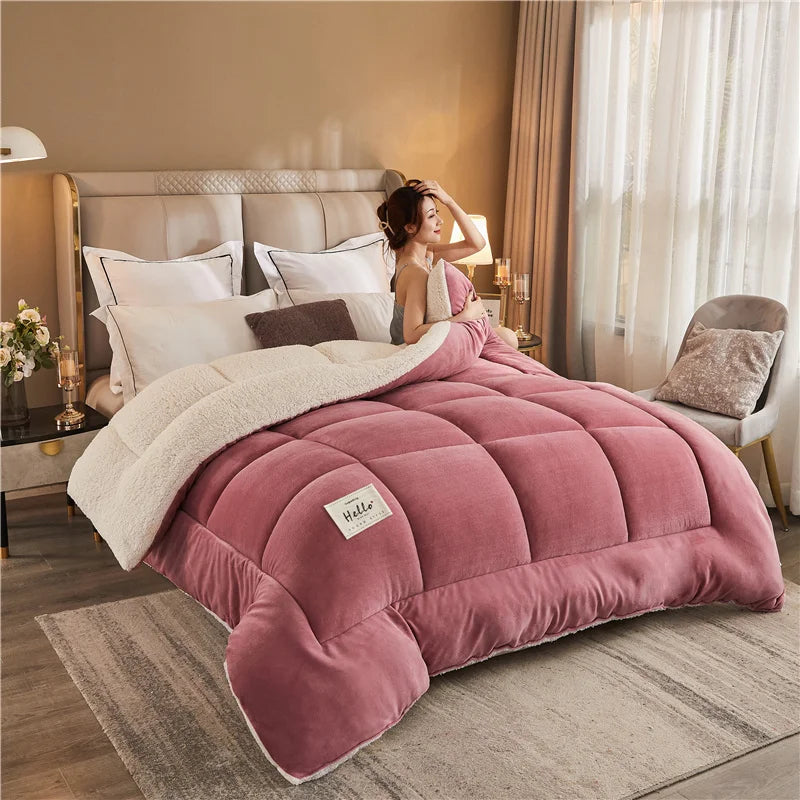 A pink weighted fleece blanket is displayed on a bed, with a woman resting her head on it in a softly lit bedroom.