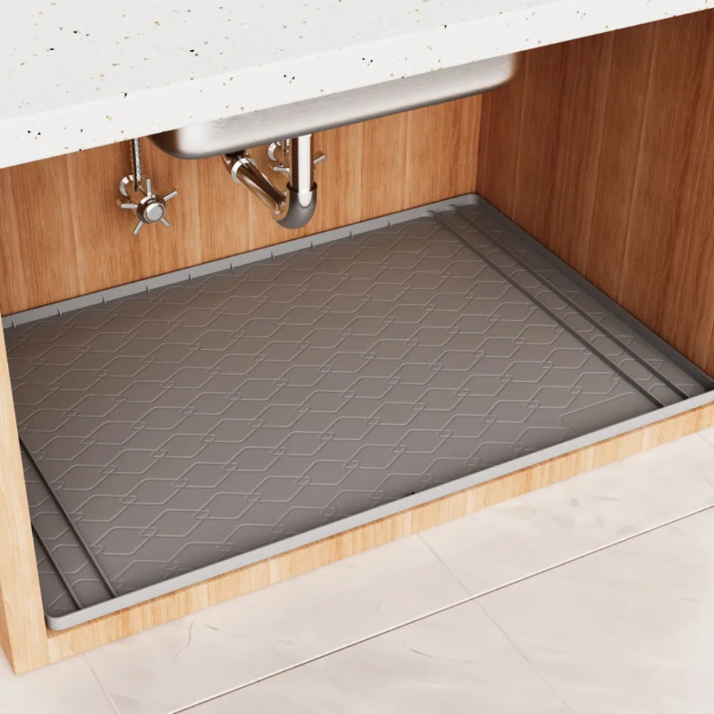 A silicone mat protecting the bottom of a kitchen cabinet under the sink.