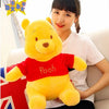 A young woman is holding a yellow Winnie the Pooh plush toy on a white couch.