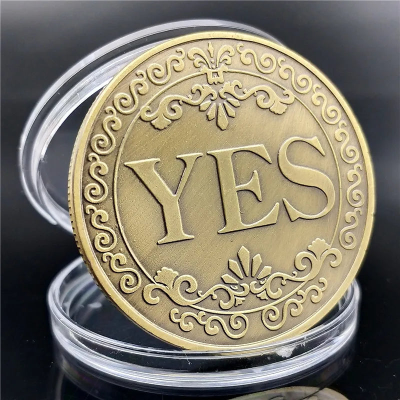 A round gold commemorative token with the word YES embossed on its surface.