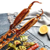 A set of natural bamboo skewers with grilled meat and vegetables are displayed on a black grill grate.
