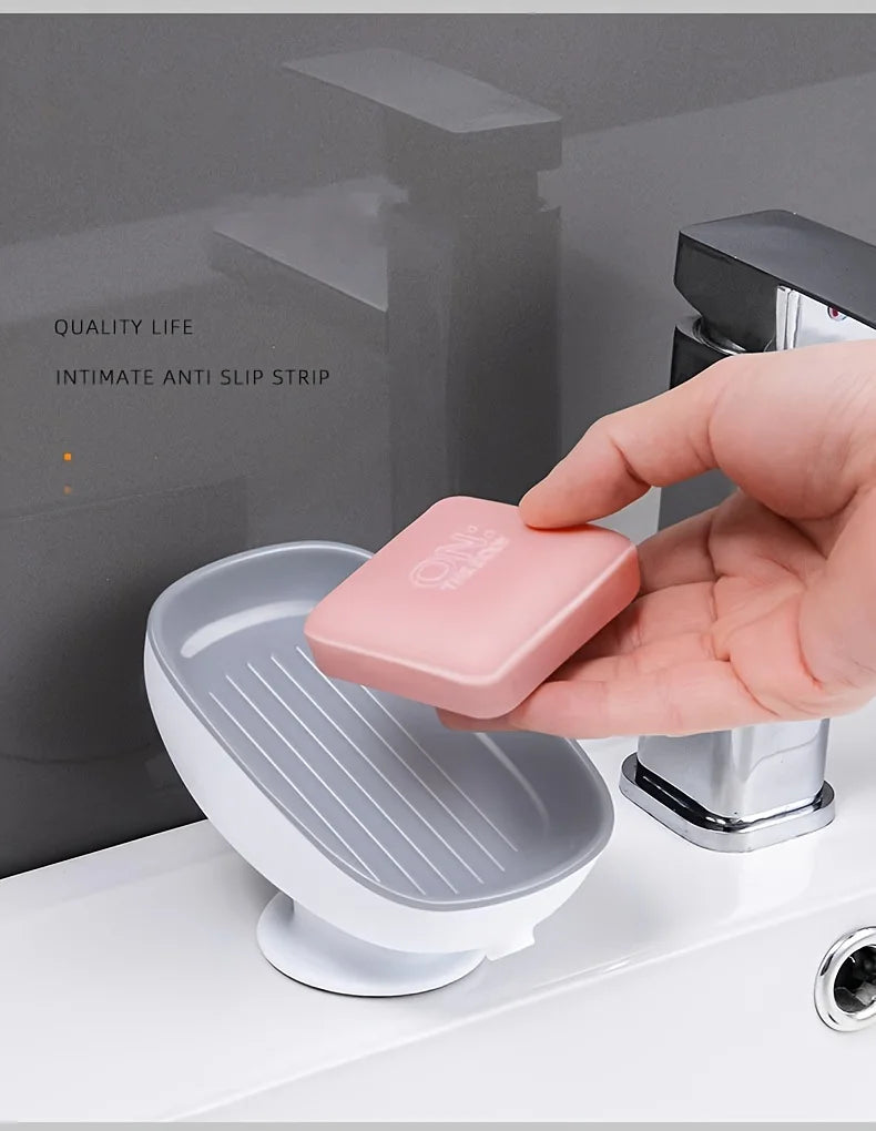 A hand places a pink leaf-shaped suction cup soap dish onto a white bathroom surface.