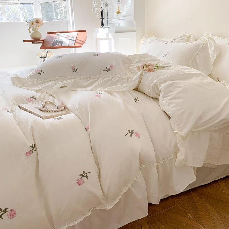 White duvet cover set with pink rose embroidery and lace details on a bed