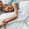 Una pareja relajándose en una cama con una almohada de espuma viscoelástica blanca, demostrando comodidad y soporte.