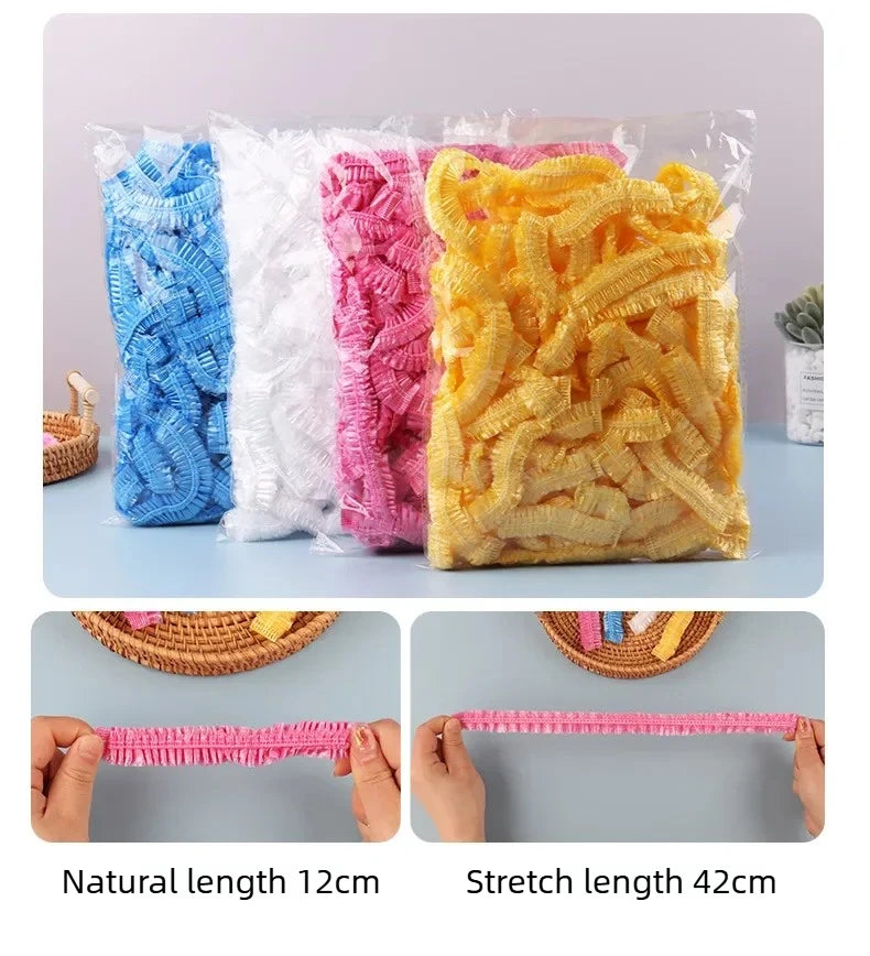 A bundle of pink, white, and yellow disposable shower caps showing natural length 12cm and stretch length 42cm