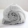 A tightly rolled light gray linen fitted sheet with deep pockets.