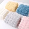 A collection of four textured bath towels in yellow, blue, gray, and pink arranged on a white surface.