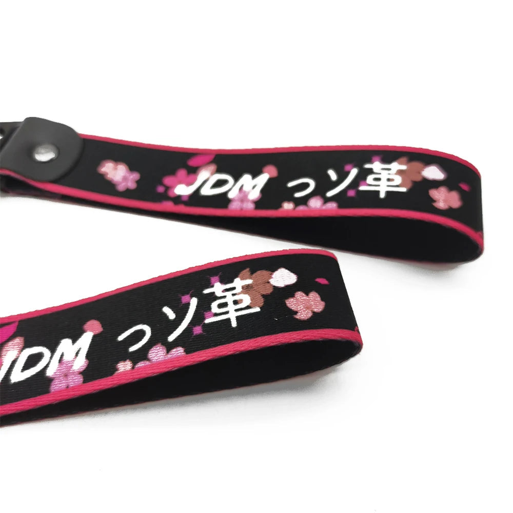 Black strap with pink floral embroidery and JDM Japanese text on a leather keychain.