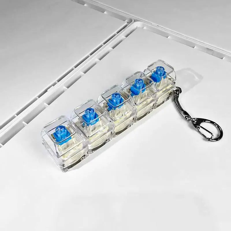 A clear plastic keychain fidget toy featuring blue LED mechanical keycaps attached to a metal ring.