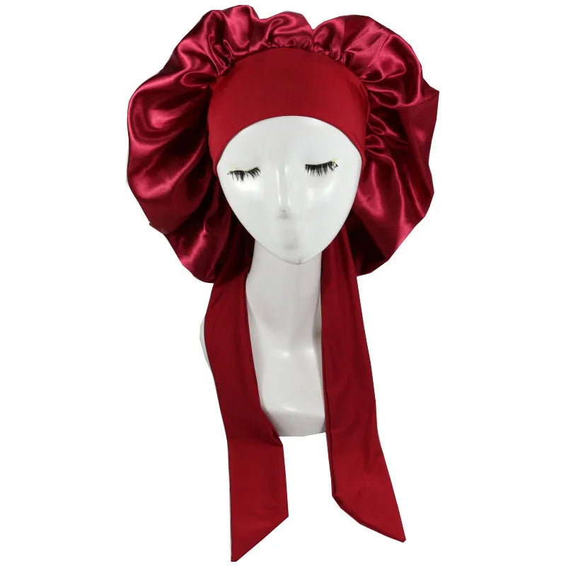 A deep red satin sleep cap with voluminous fabric draped around a white mannequin head.