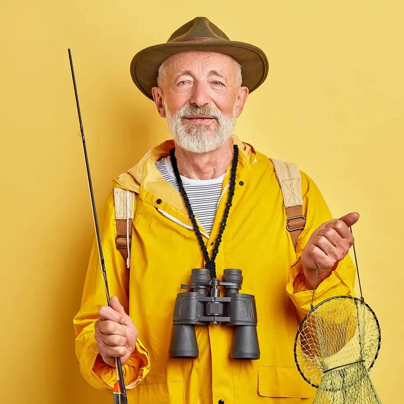 An older man wearing a wide-brimmed hat and a yellow jacket holds a fishing rod and a paracord lanyard keychain.