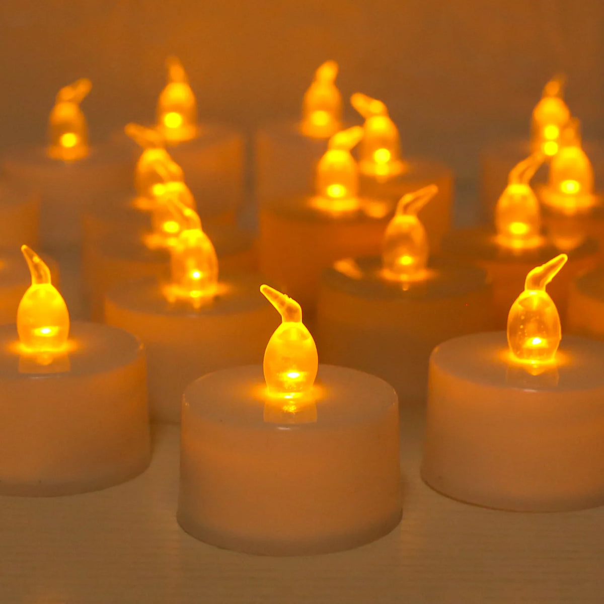 A close-up of a set of glowing yellow LED tea lights with flickering flames arranged on a surface.