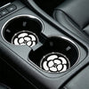 Close-up of car cup holders featuring non-slip coasters with a white camellia paw pattern.