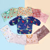 A collection of colorful waterproof long-sleeve baby bibs in various patterns and colors laid out on a light background.