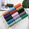 A collection of various colored macrame cord spools arranged in a fan shape on a white surface.