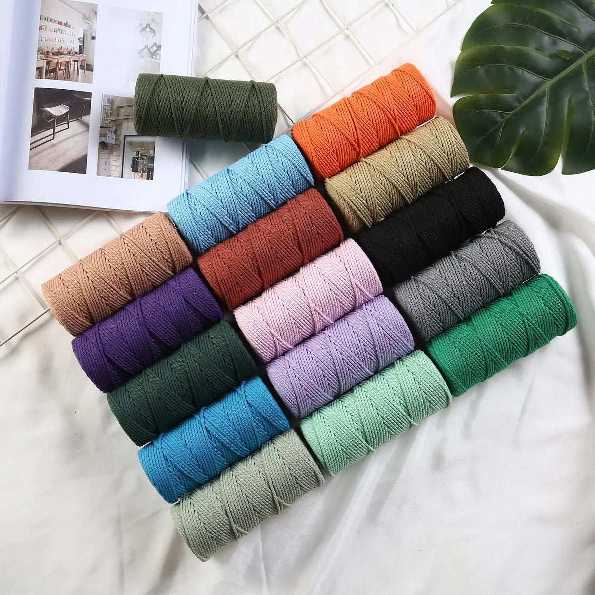 A collection of various colored macrame cord spools arranged in a fan shape on a white surface.