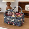 A dark floral patterned quilted fabric storage basket holding a glass bottle, resting on a wooden surface.