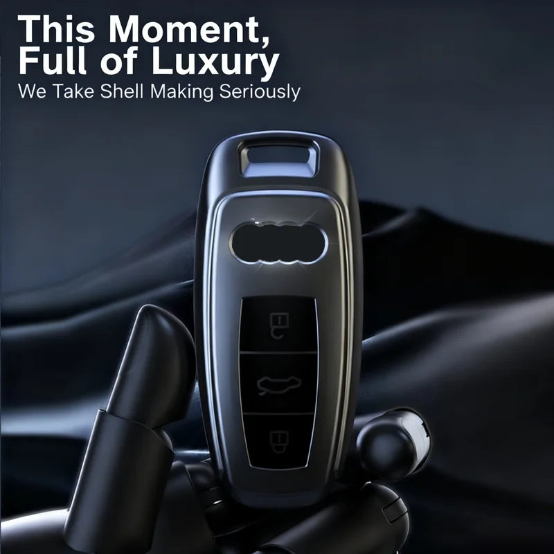 A titanium gray Audi key fob cover in a sleek case is shown against a dark background.