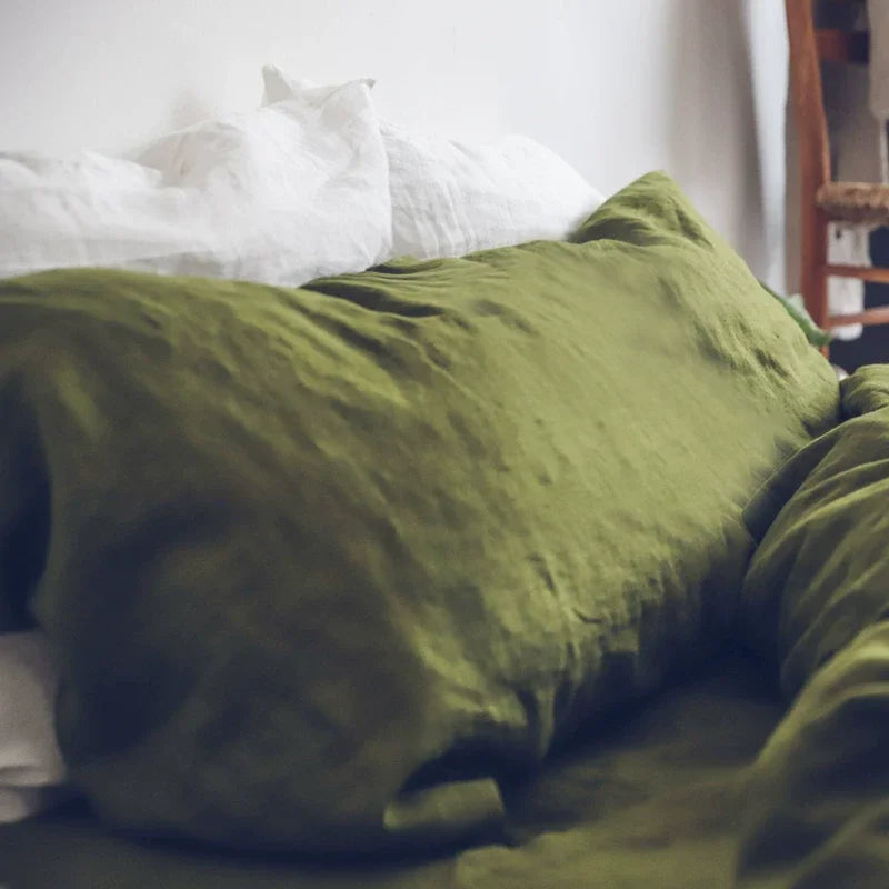 A close-up of a textured olive green linen pillowcase resting on white bedding.