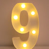 A glowing yellow LED letter night light shaped like the number 9, illuminating the surface it rests on.